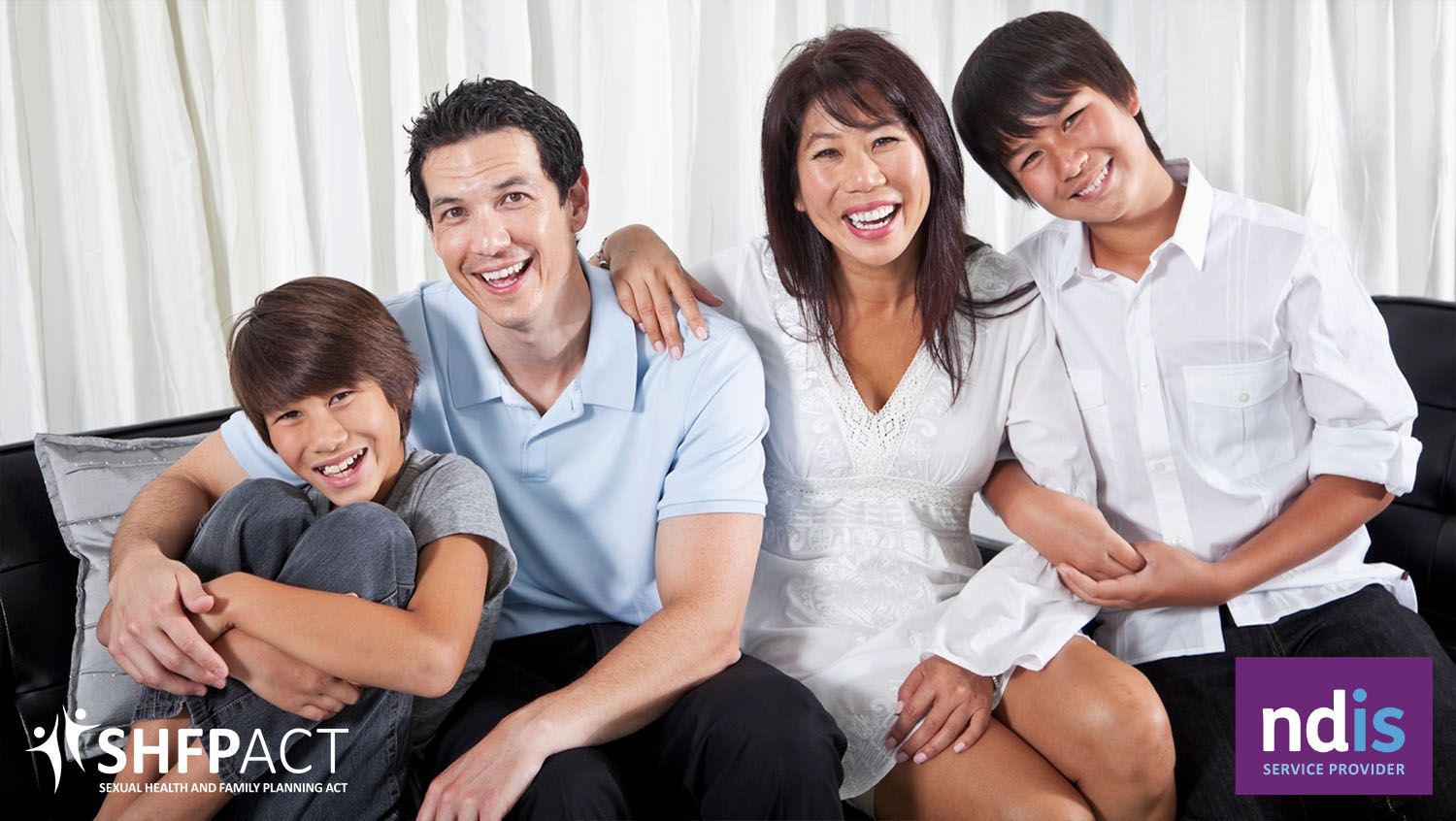 Happy family of four sitting on couch.