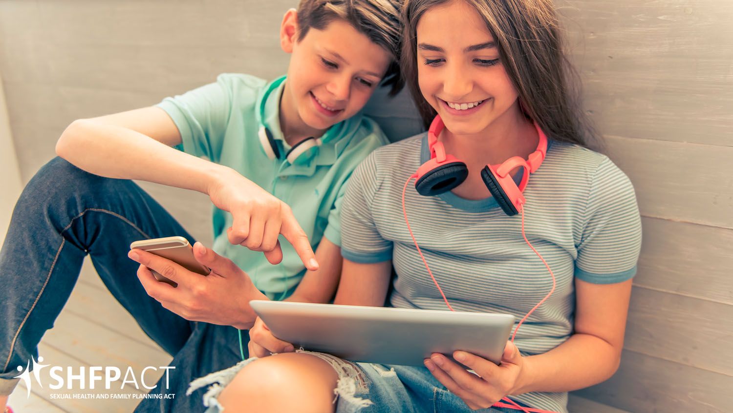 Young boy and girl sitting on the floor looking at an iPad.